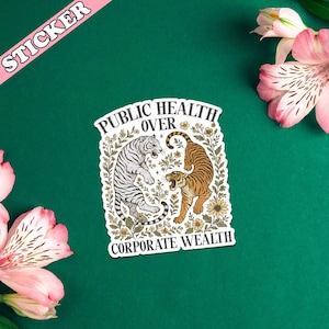 May include: A sticker with the text "PUBLIC HEALTH OVER CORPORATE WEALTH" featuring illustrations of two tigers. One tiger is white with black stripes, and the other is orange with black stripes. The sticker has a pink banner that says "STICKER".