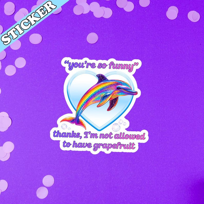Peut inclure: Autocollant avec un dauphin aux couleurs de l'arc-en-ciel dans un c&oelig;ur bleu. Il y a les phrases "you're so funny" et "thanks, I'm not allowed to have grapefruit". Le mot "STICKER" est &eacute;crit sur une banni&egrave;re bleue.