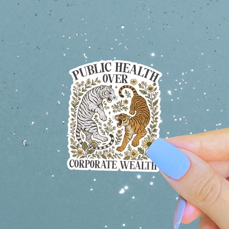 May include: A sticker with a design of two tigers, one white and one orange, framed by flowers. The text "PUBLIC HEALTH OVER CORPORATE WEALTH" is displayed above and below the tigers.