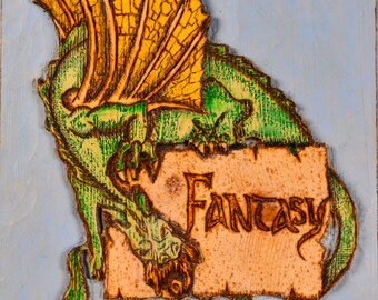 Puede incluir: Un dragón verde con alas amarillas está tallado en una señal de madera. La señal está pintada de azul claro y tiene la palabra "Fantasy" tallada en ella.