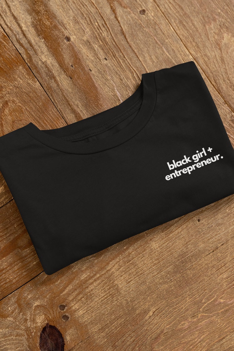 May include: Black t-shirt with the text "black girl + entrepreneur." printed in white on the front.