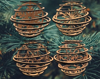 Könnte beinhalten: Vier Holzornamente mit einem Spiraldesign und Schneeflockenausschnitten. Die Ornamente bestehen aus hellbraunem Holz mit dunkelbraunen Akzenten und sind vor einem Hintergrund aus grünen Tannennadeln platziert. Die Ornamente sind kugelförmig.