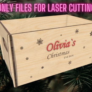 Könnte beinhalten: Eine Holzkiste mit brauner Beize und einem ausgeschnittenen Griff. Die Kiste ist mit Schneeflocken und dem Text "Olivia's Christmas Eve Box" verziert.