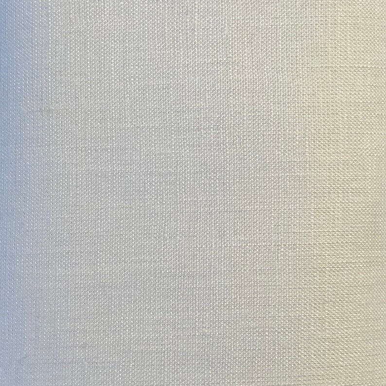 May include: A close-up view of a solid white fabric with a visible woven texture. The material features a consistent, tight grid pattern created by the interlacing of horizontal and vertical threads, resulting in a matte, uniform surface appearance.