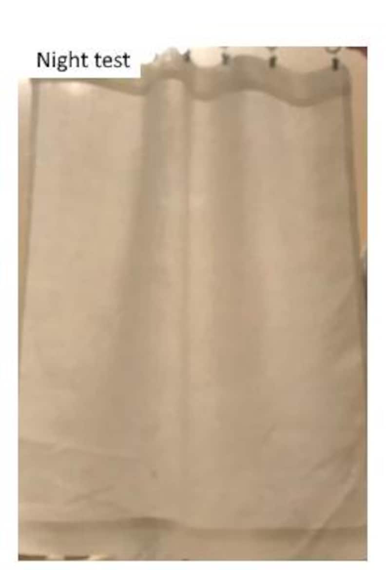 May include: A sheer, off-white curtain panel hanging from metal rings, featuring a light, translucent fabric with soft vertical folds. The text 'Night test' is printed in black in the upper left corner of the image, indicating a light-blocking test.