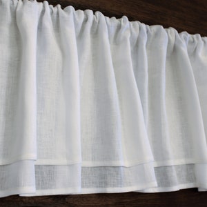 Pode incluir: Valance branca de voile com um babado duplo. A valance &eacute; feita de um tecido leve e tem um visual franzido.