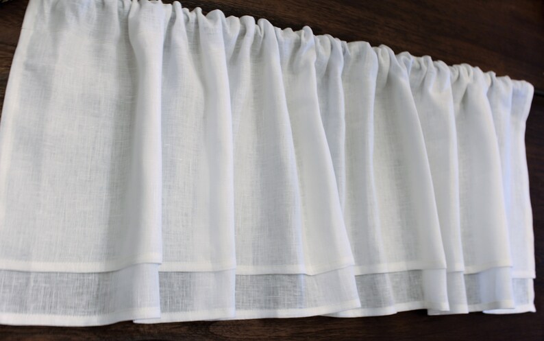 Pode incluir: Valance branca de voile com um babado duplo. A valance &eacute; feita de um tecido leve e tem um visual franzido.