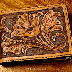 May include: A brown leather wallet with a tooled floral design. The design features a large flower with intricate details and leaves.