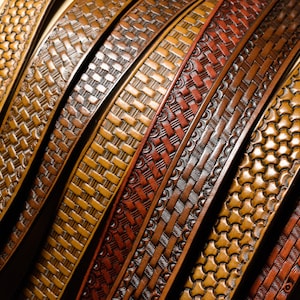 May include: Close-up of several leather straps with different embossed patterns. The straps are in shades of brown and red.