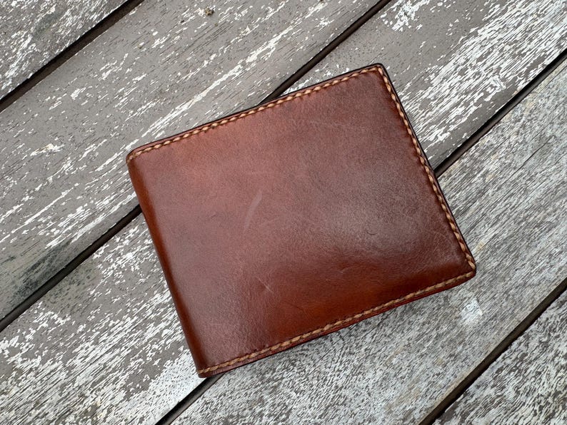 May include: A brown leather wallet with a stitched edge.