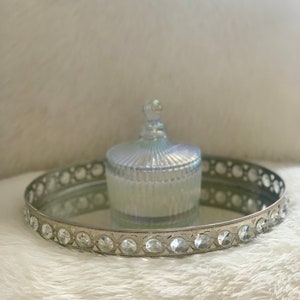 May include: A silver mirrored tray with a decorative rim and crystal accents. A clear glass jar with a lid sits on the tray.