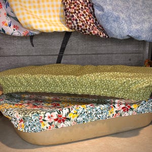 May include: Two rectangular fabric bowl covers with elastic edges. The top cover features a small green and white floral pattern. The bottom cover displays a vibrant floral print with red, yellow, and blue flowers on a white background.
