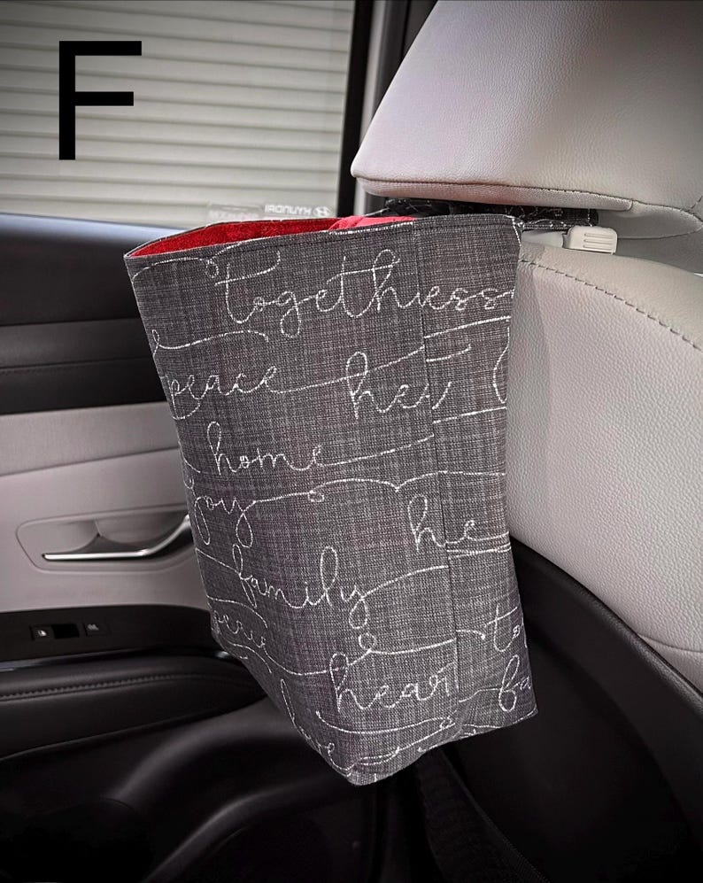 以下が含まれることがあります： グレーの布製車用ゴミ袋で、内側は赤色です。togetherness、peace、home、joy、family、heartという白い筆記体の文字がプリントされています。白いプラスチック製のクリップで車のヘッドレストに取り付けられています。