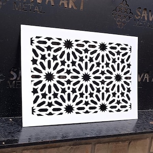 May include: A white metal decorative panel with a geometric pattern of stars and circles. The panel is mounted on a black metal shelf against a brick wall. The text "SAVA ART METAL" is visible on the wall.