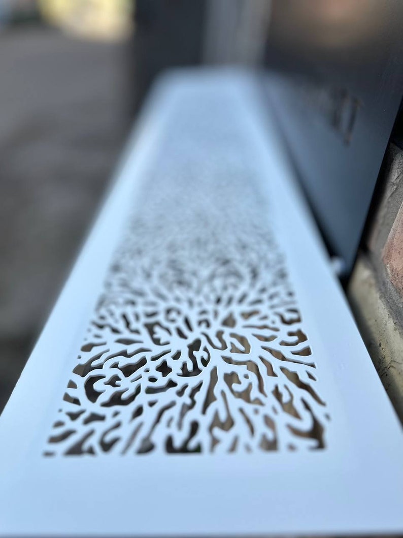 May include: White metal vent cover with a decorative cut-out design resembling a tree branch or coral.