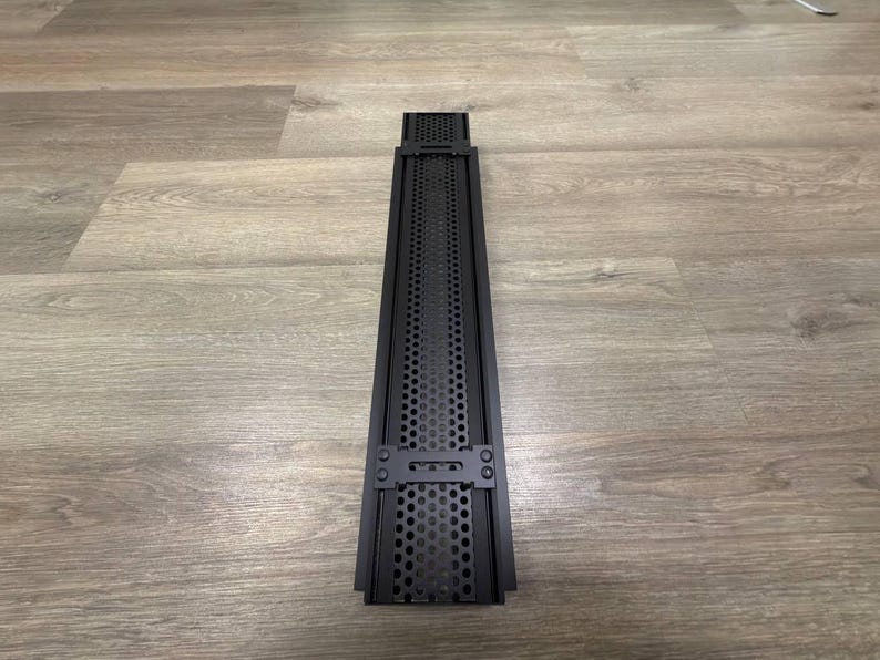 May include: Black metal vent cover with a perforated design and two metal clips on the sides.