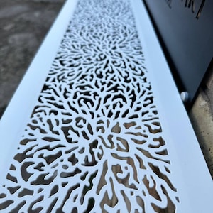 May include: White metal vent cover with a decorative, intricate, laser-cut design resembling branches or coral. The design is repeated vertically across the cover.