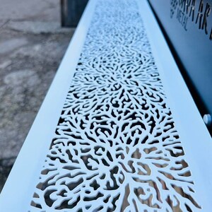 May include: A white metal panel with a decorative cutout design resembling coral. The panel is light blue and has a smooth surface.