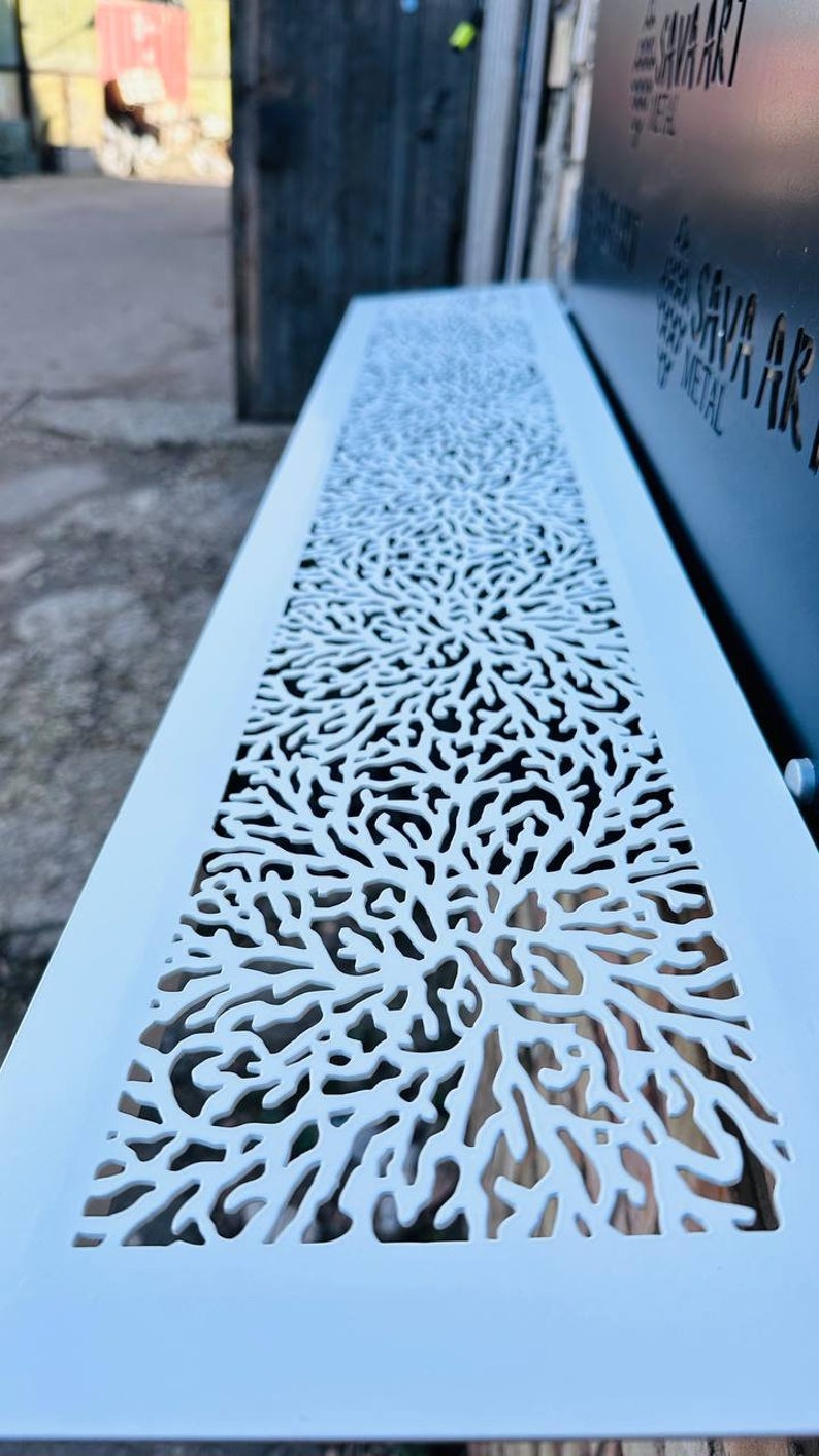 May include: A white metal panel with a decorative cutout design resembling coral. The panel is light blue and has a smooth surface.