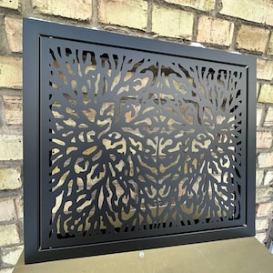 Puede incluir: Panel decorativo de metal negro con un diseño de ramas de árbol recortadas. El panel rectangular tiene un marco negro. El patrón detallado crea un efecto visual llamativo, adecuado para la decoración interior o exterior.
