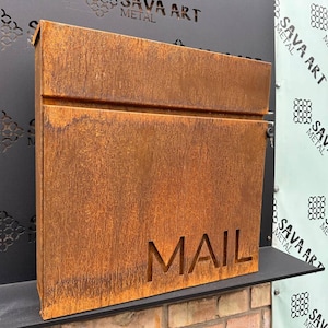 May include: A rusty metal mailbox with the word "MAIL" cut out in the front. The mailbox has a single slot for mail and a small lock on the side.