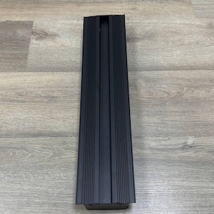 May include: A black rectangular metal light fixture with a narrow opening in the centre.