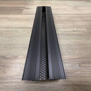 May include: Black metal vent cover with a long, narrow rectangular shape and a series of vertical lines on the surface. The vent cover has a perforated metal insert in the centre.