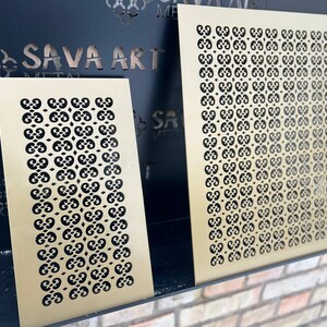 May include: Two gold metal decorative panels with a repeating geometric pattern. The panels are displayed on a black surface.