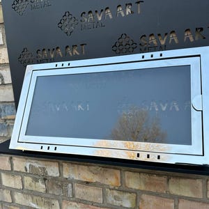 以下が含まれることがあります： 長方形の窓と表面に「SAVA ART METAL」という文字が繰り返されている銀色の金属製のドアです。
