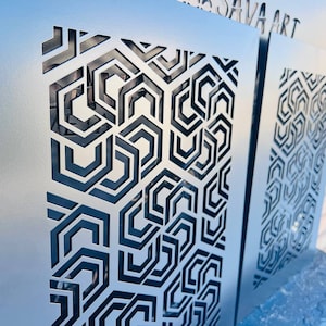 May include: Two metal wall panels with a geometric pattern cut out. The panels are silver and the cutouts are black. The text "SAVA ART" is visible on the top of the right panel.