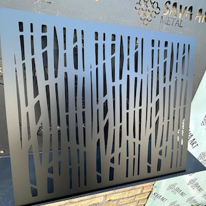 Puede incluir: Una pantalla de metal gris oscuro con un diseño de ramas de árboles. La pantalla tiene cortes verticales y diagonales que se asemejan a troncos y ramas de árboles. El logotipo de SAVA ART METAL es visible en el fondo.