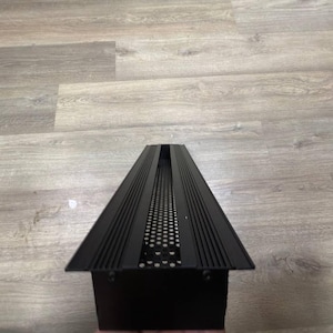 May include: Black metal vent cover with a rectangular shape and a series of horizontal lines and a grid pattern.