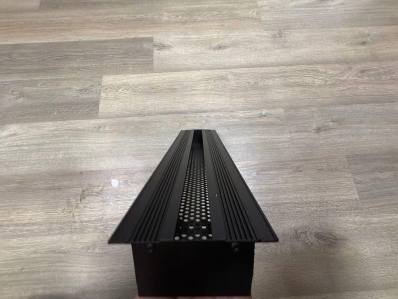 May include: Black metal vent cover with a rectangular shape and a series of horizontal lines and a grid pattern.