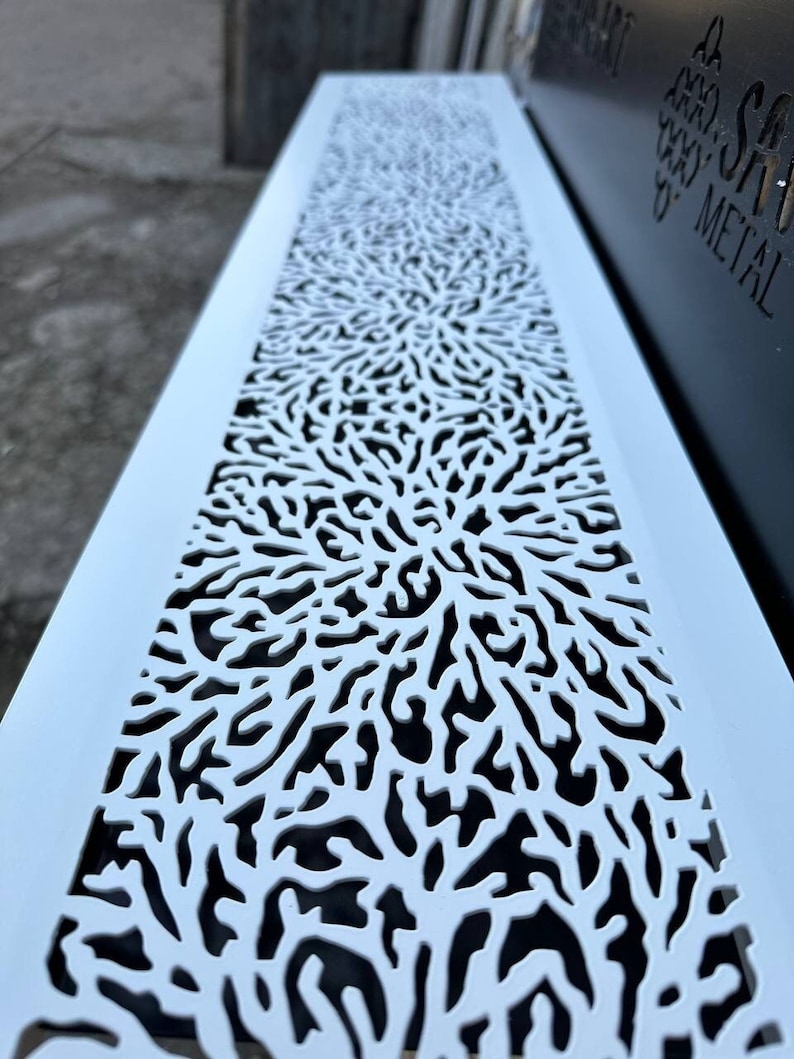 May include: White metal vent cover with a decorative, intricate, floral-like pattern. The vent cover is made of metal and has a white finish.