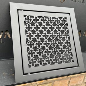 以下が含まれることがあります： 星形の装飾的なパターンが施された黒い金属製の換気口カバー。換気口カバーには「Sava Metal Art」のラベルが貼られています。