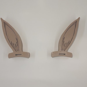 May include: Two brown bunny ears made of plastic. The ears are designed to be worn as a headband.