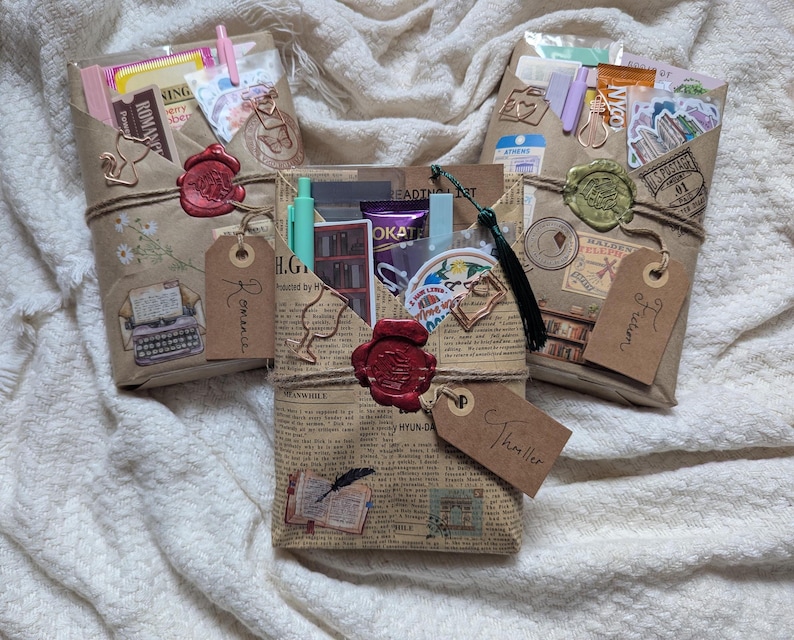 May include: Three gift packages wrapped in brown paper, tied with twine, and sealed with wax stamps. Each package contains various items, including stickers, pens, and tags labeled "Romance", "Fiction", and "Thriller". The packages are decorated with vintage-style illustrations and text.