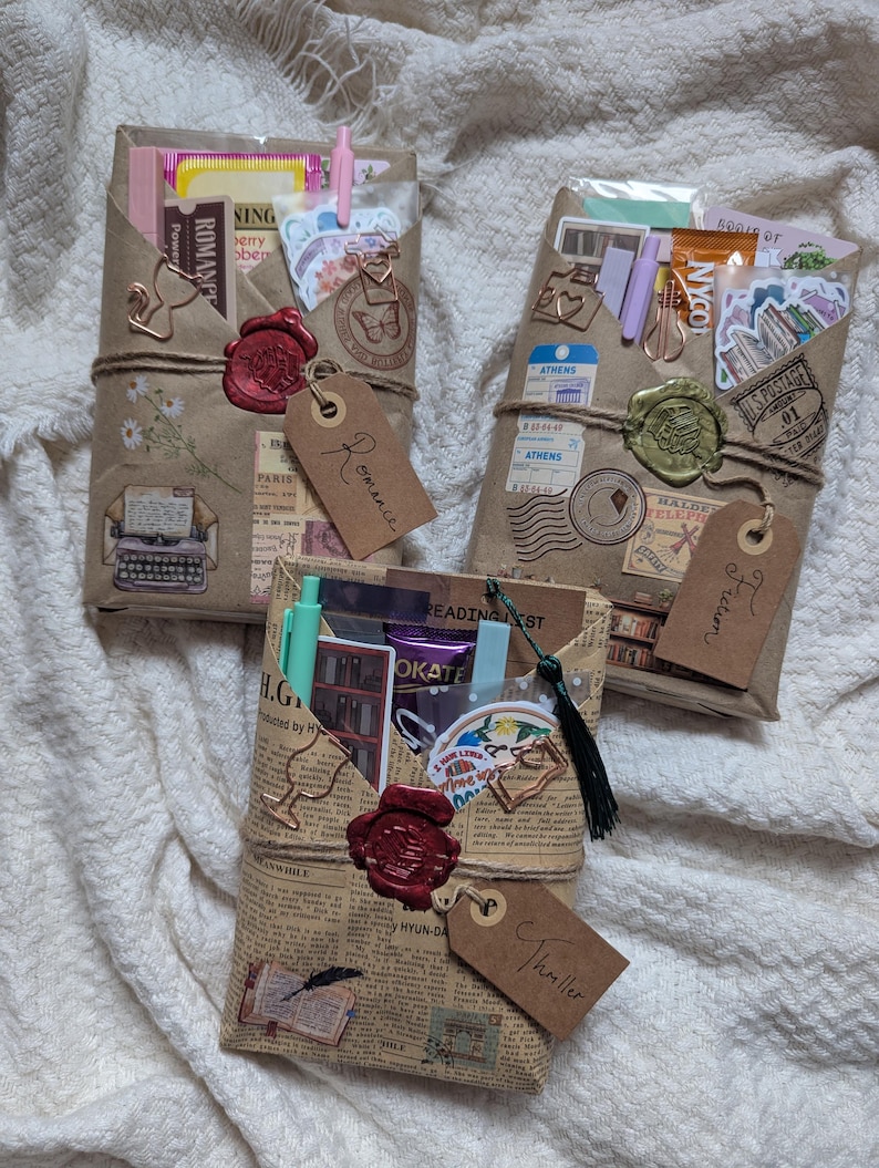 May include: Three wrapped gifts, each with a different theme: Romance, Fiction, and Thriller. The gifts are wrapped in brown paper and newspaper, sealed with wax, and adorned with tags. Each gift contains stickers, pens, and other small items.