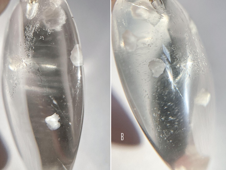 May include: Close-up of two clear quartz crystals with white inclusions. The crystals are oval shaped and have a smooth, polished surface.