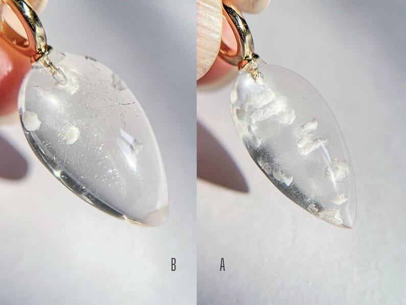 May include: A clear teardrop-shaped pendant with a gold bail. The pendant has a cloudy, milky appearance with white inclusions.