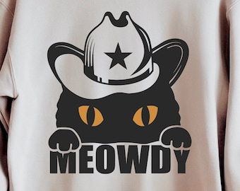 May include: A light beige sweatshirt with a black cat wearing a cowboy hat with a star on it. The cat is peeking out from behind the hat and the text "MEOWDY" is printed below the cat.