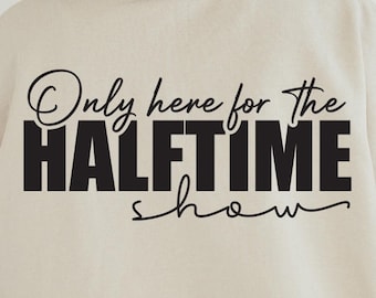 May include: A beige sweatshirt with the text "Only here for the HALFTIME show" printed in black.