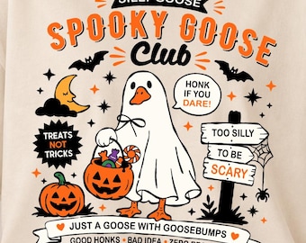 May include: A cream-colored t-shirt featuring a graphic of a goose dressed as a ghost holding a pumpkin candy bucket. The design includes text reading SILLY GOOSE SPOOKY GOOSE CLUB, HONK IF YOU DARE, TREATS NOT TRICKS, and TOO SILLY TO BE SCARY.