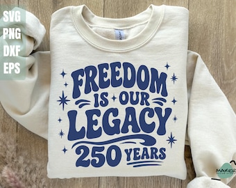 May include: Cream-colored sweatshirt with the text "FREEDOM IS OUR LEGACY 250 YEARS" in navy blue. The design includes star accents. The sweatshirt is folded, with the sleeves visible. The image also shows the file types SVG, PNG, DXF, and EPS.