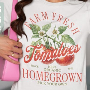 May include: White t-shirt with a red and green graphic design that says "Farm Fresh Tomatoes" with a tomato illustration. The text also says "Since 1976, 100% Organic, Homegrown, Pick Your Own."