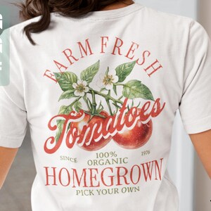 May include: White t-shirt with a red and green graphic design that says "Farm Fresh Tomatoes Since 1976 100% Organic Homegrown Pick Your Own".