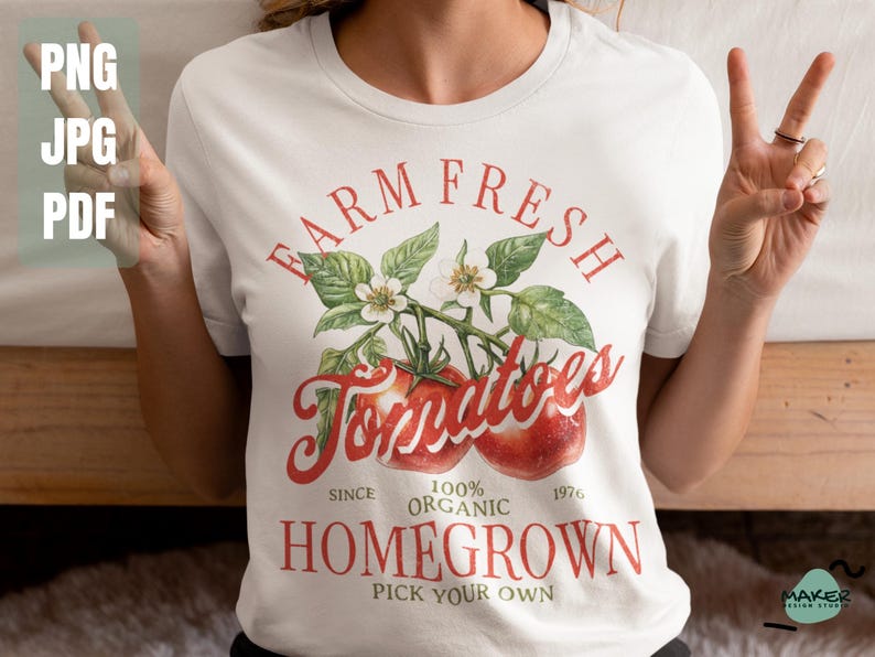 May include: White t-shirt with a vintage-style graphic design featuring a tomato vine with red tomatoes and the text "FARM FRESH Tomatoes SINCE 100% ORGANIC 1976 HOMEGROWN PICK YOUR OWN".