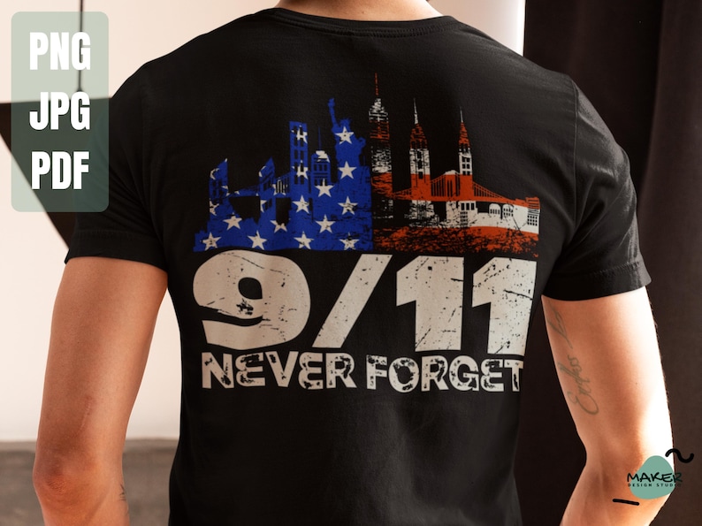 May include: Black t-shirt featuring a distressed graphic commemorating 9/11. The design includes a skyline with the Statue of Liberty and other buildings, with the American flag colors. The text "9/11 NEVER FORGET" is prominently displayed.