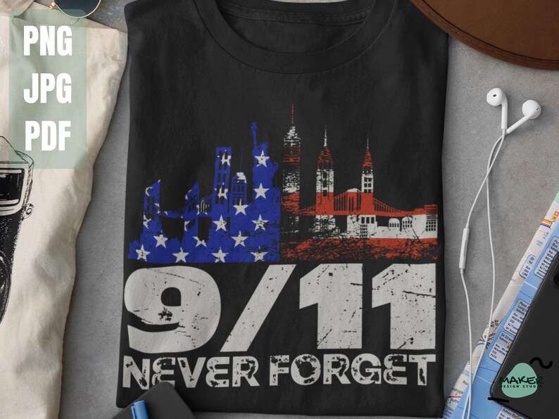 May include: Black t-shirt with a distressed graphic of a skyline and American flag design. The text "9/11 Never Forget" is printed below the graphic in white. The shirt is a tribute to the events of September 11th.