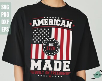 May include: Black t-shirt featuring a patriotic design. The design includes the text "AMERICAN MADE" above a stylized American flag with the text "EST. 1776" in a circle. The phrase "BUILT ON FREEDOM" is at the bottom.
